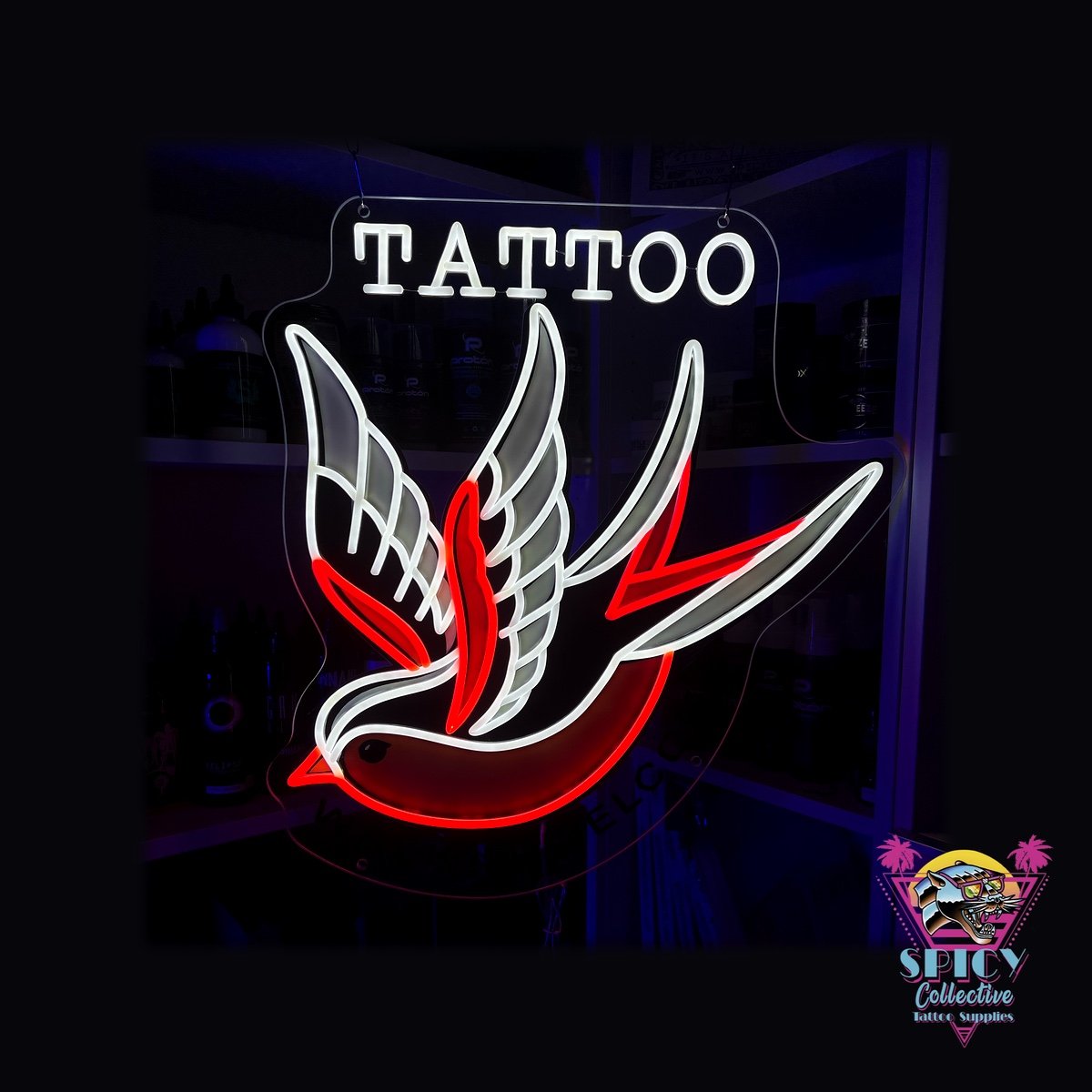 Tänd LED-neonskylt med en svala i vitt och rött och texten Tattoo